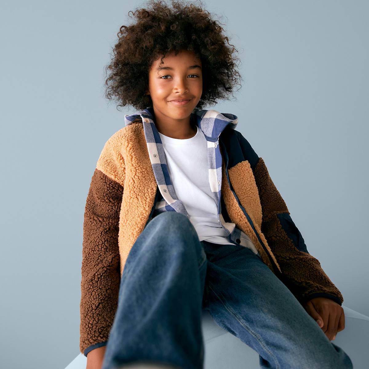 Boy wearing brown jacket, white T-shirt and jeans
